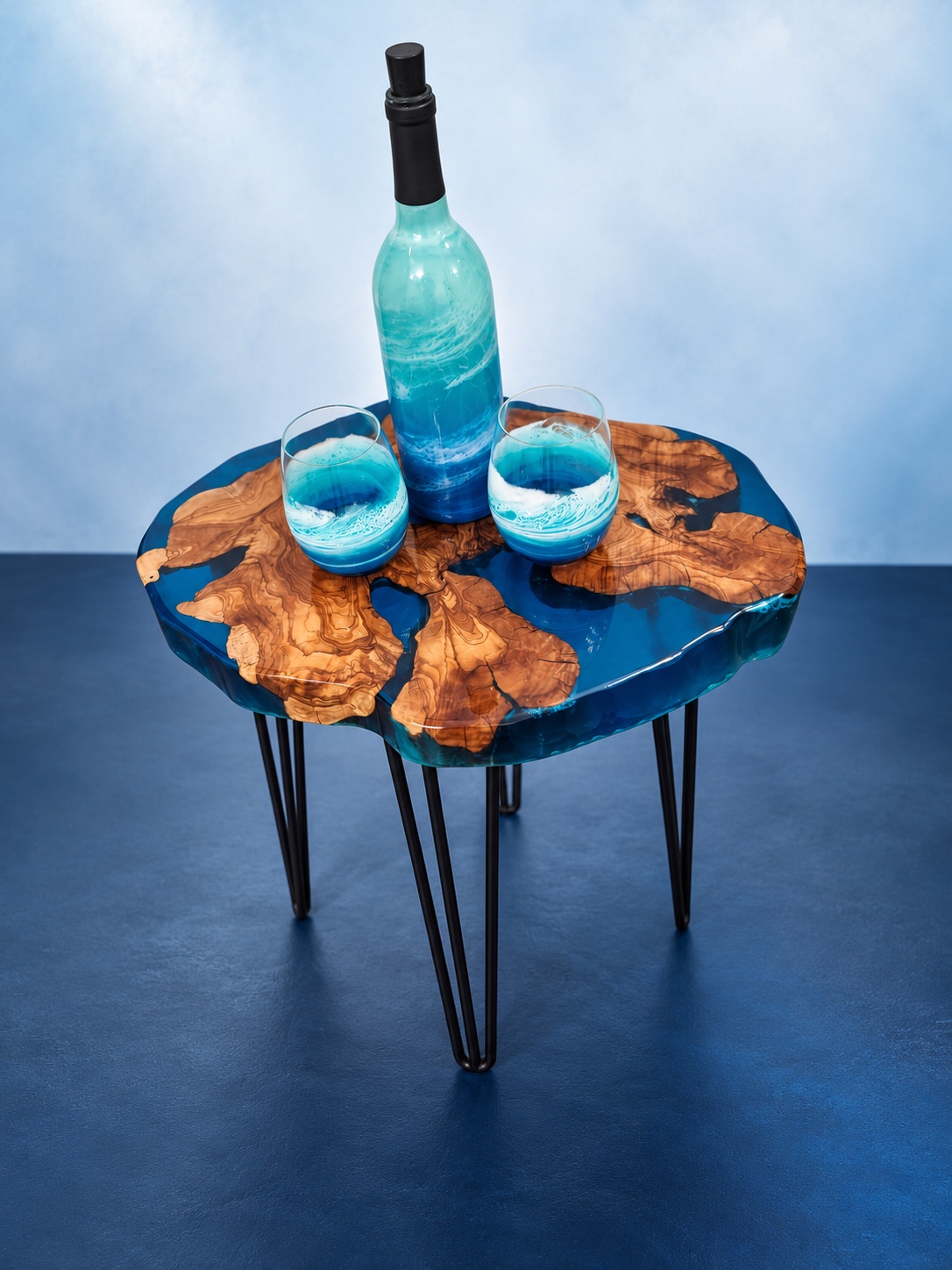Turquoise wave resin bottle and two glasses on a blue live-edge table