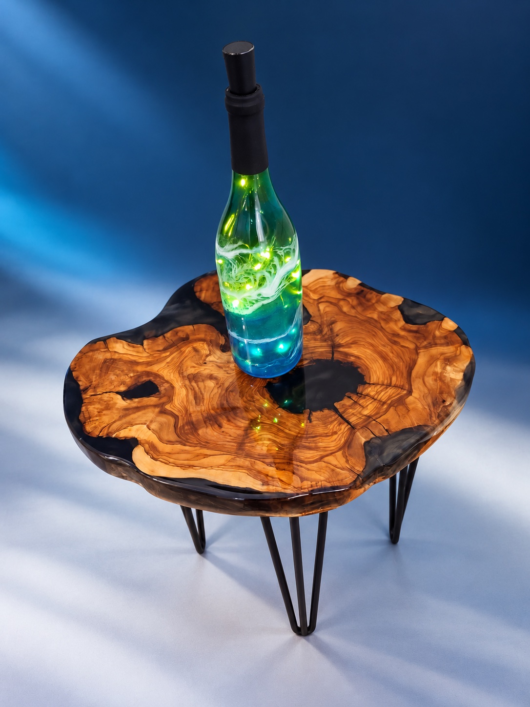Illuminated emerald and turquoise resin bottle on a live-edge table
