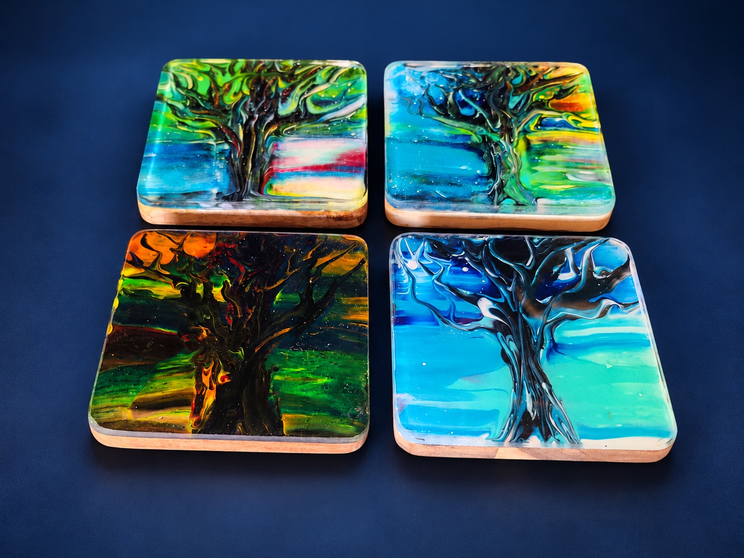 Four colorful square resin coasters with tree designs